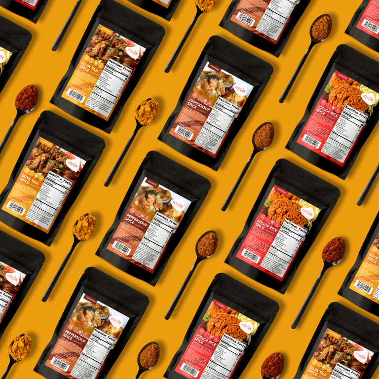 Pouches with labels of spices lay on mustard yellow background surrounded by tea spoons full of spices.